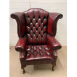 A leather wing arm chair with scrolling arms on cabriole legs