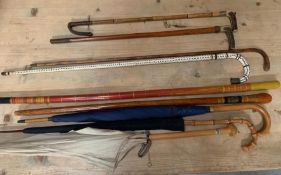 A selection of walking sticks, umbrellas, horn handled riding crops, and sun parasols