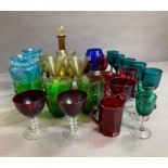 A large selection of various coloured glassware to include vases, wine and water glasses
