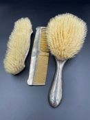 A three silver backed piece dressing table set to include two brushes and a comb.
