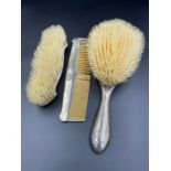 A three silver backed piece dressing table set to include two brushes and a comb.