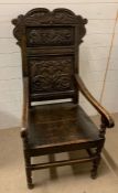 In the style of a Charles II oak caqueteuse chair, carved back, out scrolling arms, raised on turned