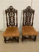 A pair of oak side chairs, with pierced and carved back with a shield flanked by dragons and scrolls