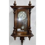 Walnut cased Vienna wall clock with white enamel face with roman numerals, with key