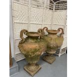 Two oversized Italian terracotta urns with twin handles, relief decorated with swags and lions.