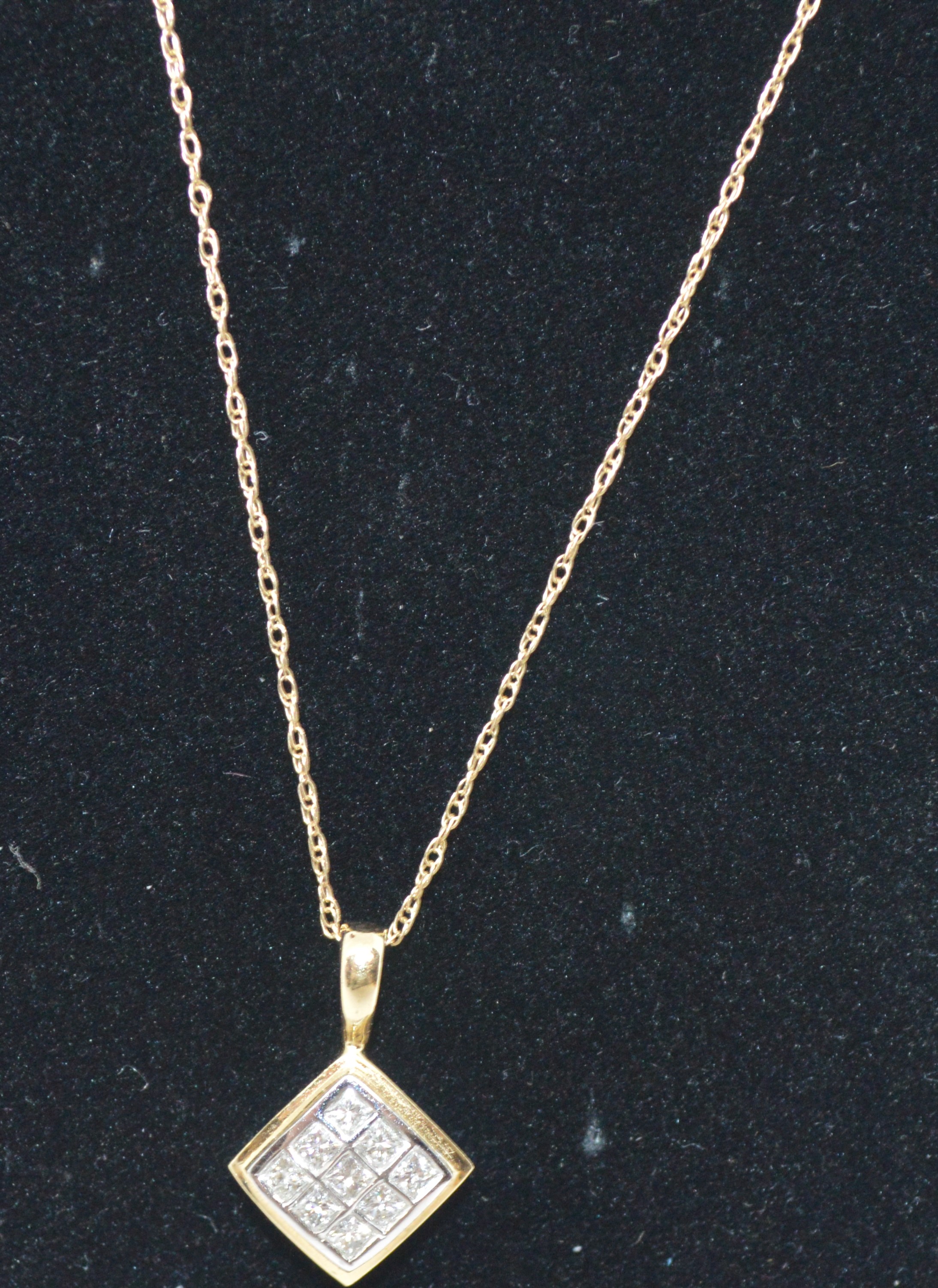 A 10k yellow gold Diamond pendant of nine diamonds set into rectangular design with gold chain, both