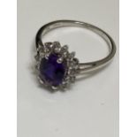 A ladies cluster ring, marked 10ct. Central oval purple stone surrounding clear stones, hallmarked