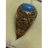 A 9ct yellow gold ring Turquoise stone with London University and tragedy mask detailing to mount,