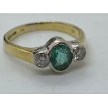 A yellow gold ring, with central oval green stone with two diamonds set either side, hallmarked