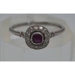Art deco style ring, raised central ruby with diamonds to surround, tested as 14ct white gold,