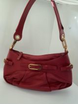 A genuine Coccinelle leather handbag featuring a striking red soft leather with contrasting gold