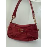 A genuine Coccinelle leather handbag featuring a striking red soft leather with contrasting gold