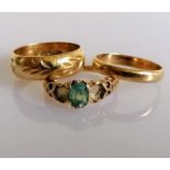 Two gold wedding bands, one with etched decoration and a gem-set ring (two stones missing), all