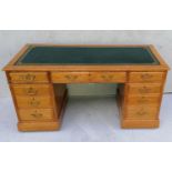 A Georgian-style light oak twin pedestal desk with tooled leather inset over an arrangement of