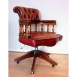 A captain's swivel office chair in faded leather button back upholstery, brass studs and castors, 90