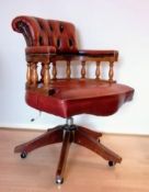 A captain's swivel office chair in faded leather button back upholstery, brass studs and castors, 90