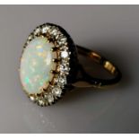 An oval opal cluster ring with sixteen round brilliant-cut diamonds, approximate total weight 1.20