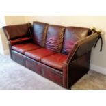A vintage Knole three-seat drop arm sofa upholstered in red studded leather, 102 h x 230 w x 90 d