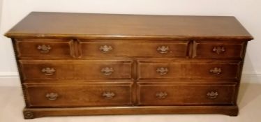 A Harrods Royal Oak Furniture dresser base with an arrangement of seven drawers with brass drop