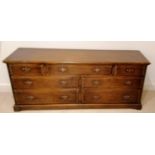 A Harrods Royal Oak Furniture dresser base with an arrangement of seven drawers with brass drop