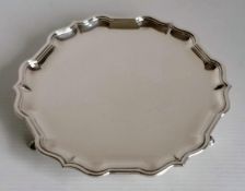 A Georgian-style circular silver salver with pie-crust rim on three hoof feet by Roberts & Belk,