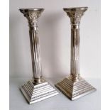 A matched pair of Corinthian-style silver candlesticks with removable sconces, beaded decoration