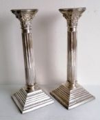 A matched pair of Corinthian-style silver candlesticks with removable sconces, beaded decoration