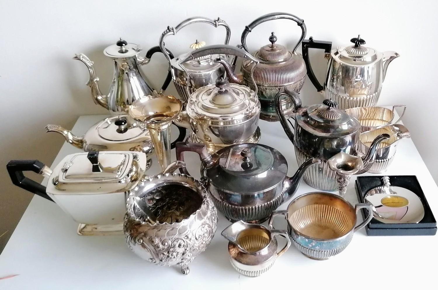 An assortment of silver plated tea kettles, coffee pots, etc