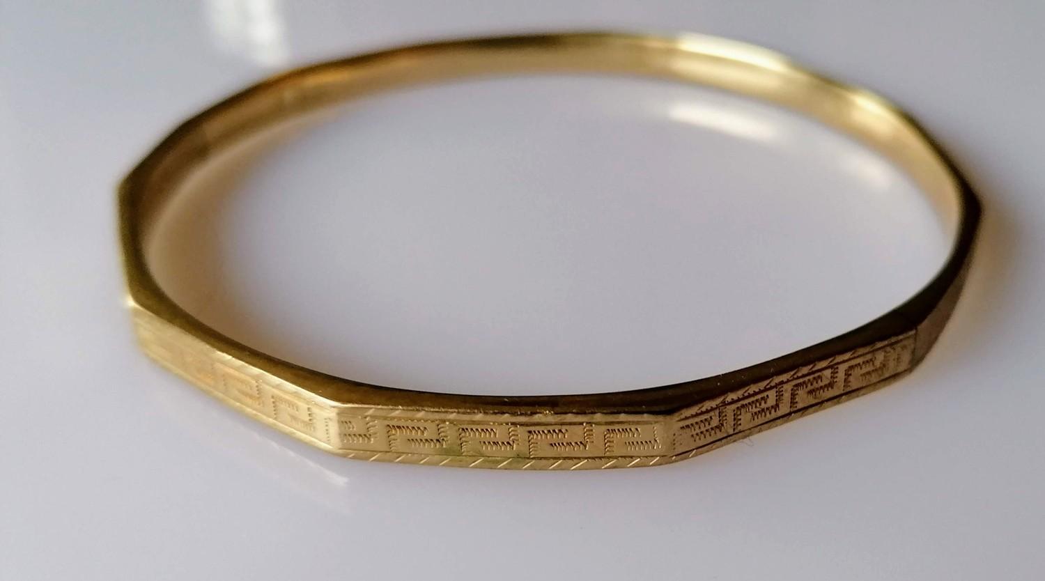 A 9ct yellow gold bangle with faceted decoration, marks rubbed, 12.5g