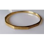 A 9ct yellow gold bangle with faceted decoration, marks rubbed, 12.5g
