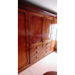 A late Georgian mahogany gentleman's wardrobe with shaped cornice, central cupboard comprising