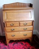 An Arts & Crafts oak bureau with fitted interior, drawers under, carved brass handles and pierced