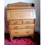 An Arts & Crafts oak bureau with fitted interior, drawers under, carved brass handles and pierced