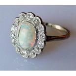 An oval opal (9mm x 6mm) cluster ring with 14 round brilliant-cut diamonds, total approximate