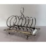 A late Victorian silver toast rack with gadroon edge decoration raised on claw and ball feet,