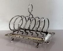 A late Victorian silver toast rack with gadroon edge decoration raised on claw and ball feet,