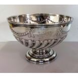 A late Victorian silver punch bowl with embossed swag and half-flute decoration on a stepped foot,