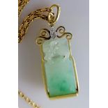 A carved jade pendant surmounted by a lion in a gold setting, 32mm x 12mm and chain, both hallmarked