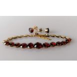 A garnet and gold bracelet with matching earrings, unmarked, the eleven garnets range from 0.5-1.0