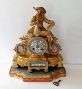 A 19th century French gilt mantle clock surmounted by a carved figure, Roman numerals (glass