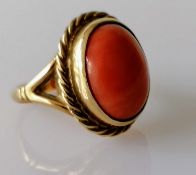 An oval cabochon coral dress ring on a yellow gold setting with rope-twist design, coral 15mm x