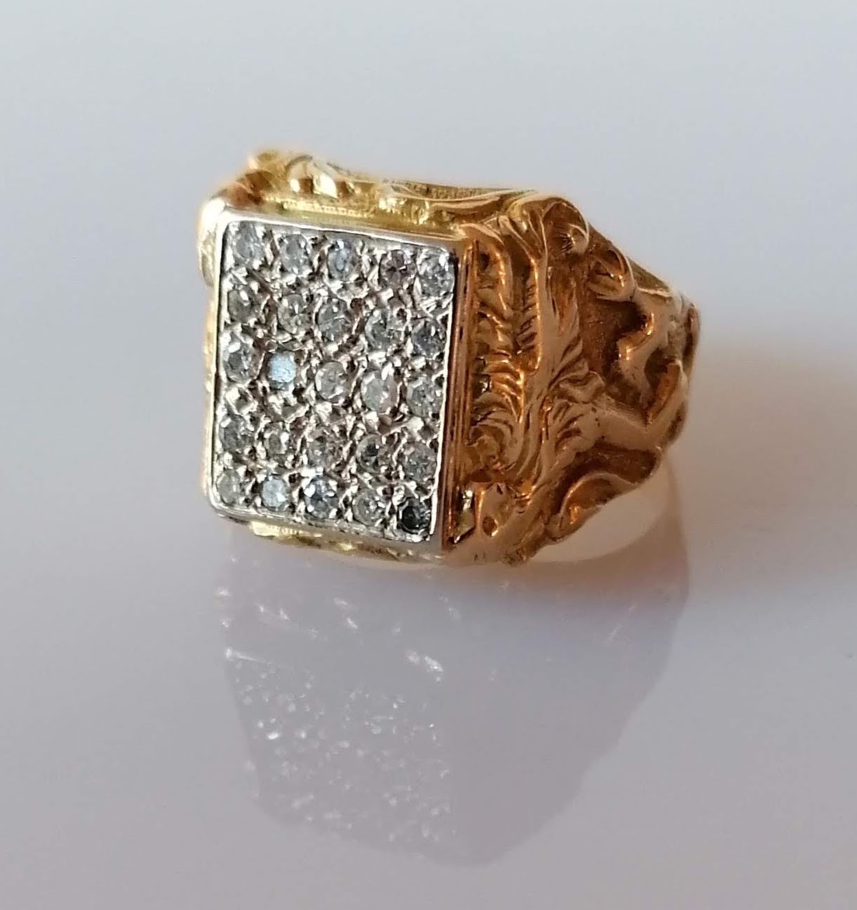 A larger yellow gold signet ring with a panel of twenty-five round-cut diamonds, each