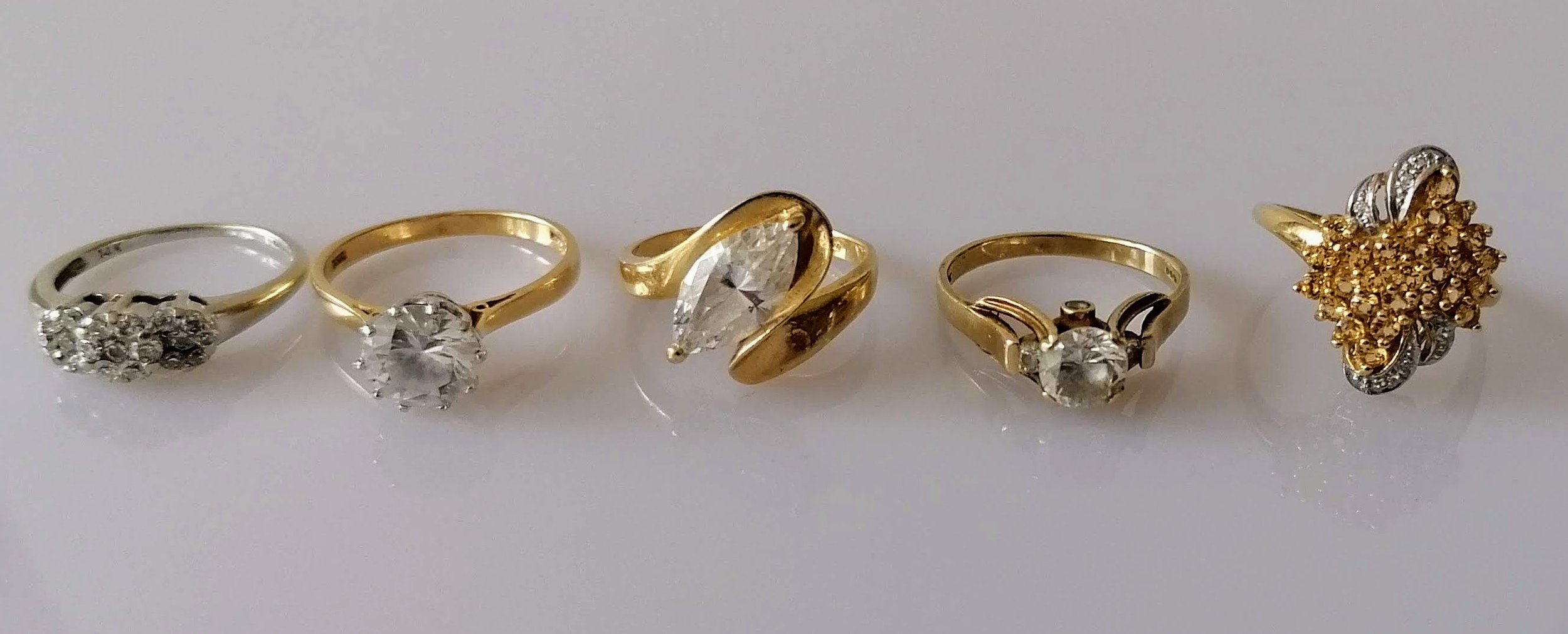 A three-cluster graduated diamond ring in a white gold claw setting; three gem-set yellow gold dress