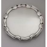 An Edwardian silver salver with pie-crust rim on four scroll feet by James Dixon & Sons Ltd.,