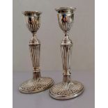 A pair of Victorian silver candlesticks with fluted decoration on oval spreading bases by Henry