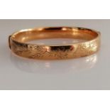 A 9ct yellow gold bangle with etched decoration, 62mm x 58mm, hallmarked for Birmingham, 1970, clasp