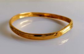 A 22ct gold bangle with reeded decoration, stamped 916, slightly buckled, 11.6g