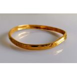 A 22ct gold bangle with reeded decoration, stamped 916, slightly buckled, 11.6g