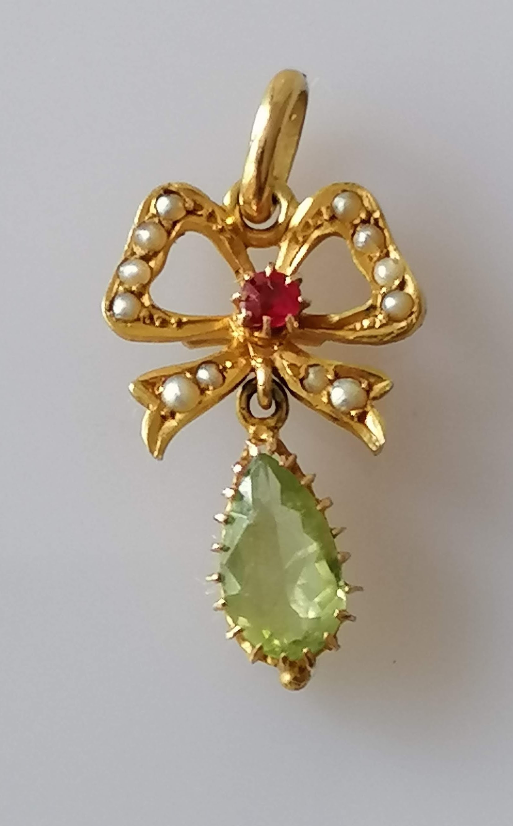 A Victorian gold ribbon pendant with seed pearl, garnet and peridot decoration, 36mm x 15mm,