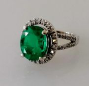 An oval emerald and diamond cluster ring, 10 x 7.9 x 5.35 mm weighing a calculated 2.50 carats